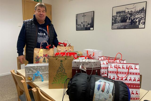 Auf einem Tisch vor Detlef Pourie aus Waltrop stehen mehrere weihnachtliche Geschenketüten und ein zusammengerollter Schlaftsack.