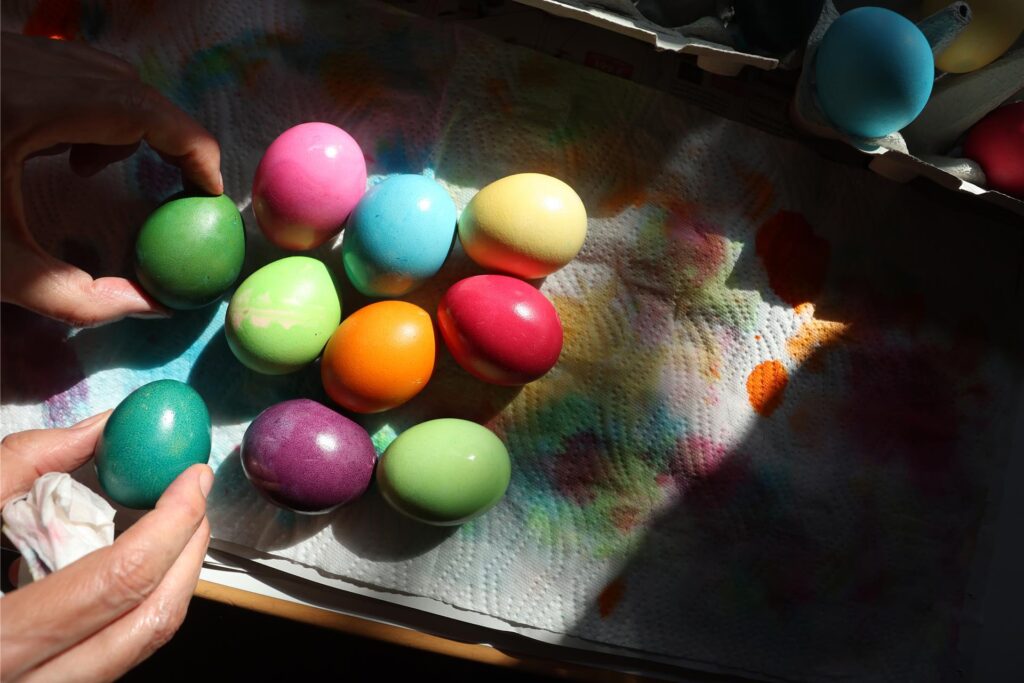 Eine Person hält bunte Ostereier in den Händen und weitere Eier liegen auf einem Tuch Eine Person hält bunte Ostereier in den Händen und weitere Eier liegen auf einem Tuch