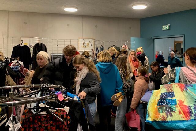 Menschen stöbern bei der Kleidertauschparty des Castroper Klimapakts an verschiedenen Kleiderständern und schauen sich die Kleidung an.