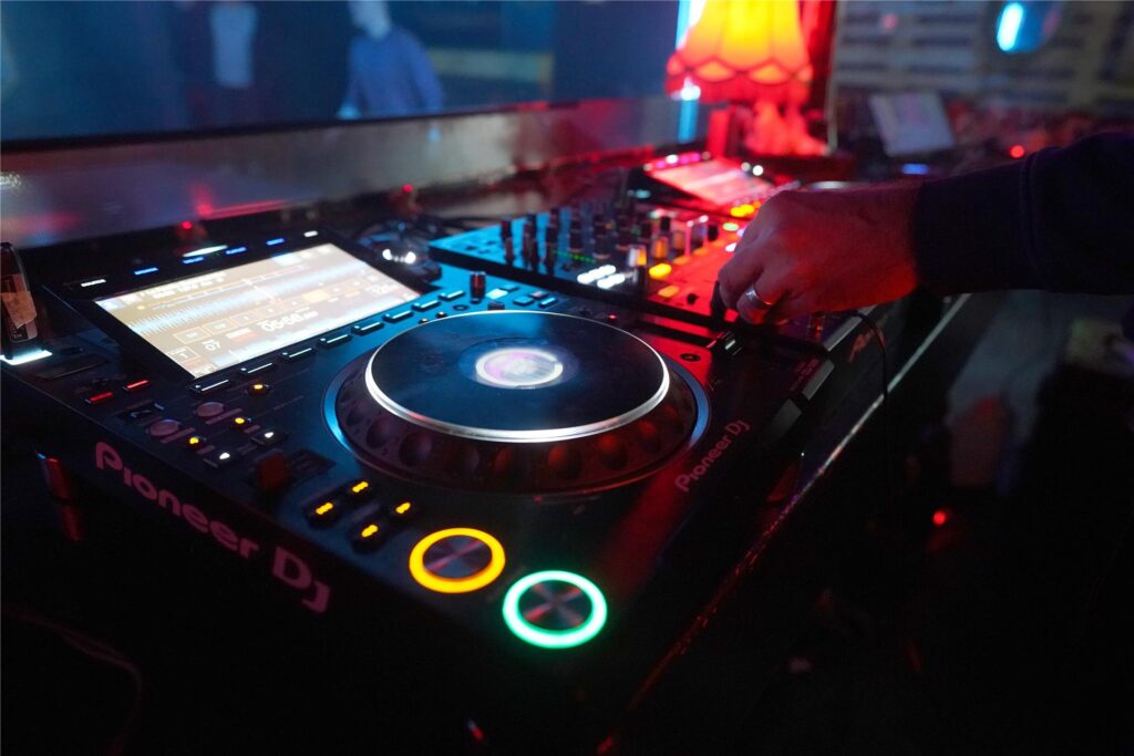Ein DJ drückt Knöpfe auf einem DJ-Pult