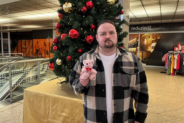 Pierre Barth hält einen rosa Teddybären in der Hand und steht vor einem Weihnachtsbaum im Marler Stern.