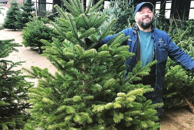Der Heubauer Gregor Jörgens posiert auf seinem Hof neben den Weihnachtsbäumen aus dem Sauerland.