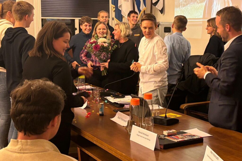 junge Leute klatschen einer Frau stehend Beifall, sie hat Blumen in der Hand. junge Leute klatschen einer Frau stehend Beifall, sie hat Blumen in der Hand.