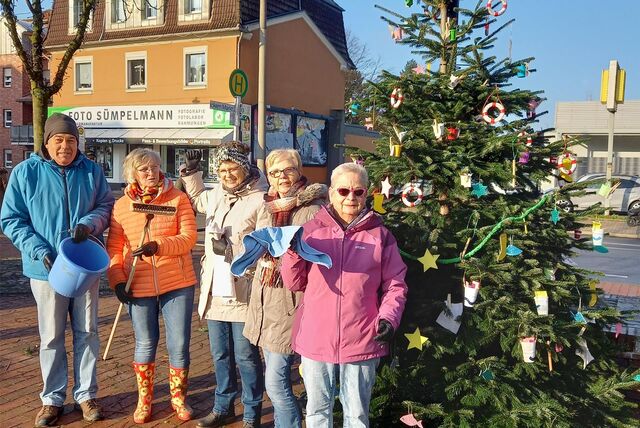 Klaus-Dieter Tesch vom Verein Menschen an der Emscher beim Schmücken des Weihnachtsbaums mit anderen Mitstreitern und Mitstreiterinnen. An den Zweigen baumeln Gummistiefel, Rettungsringe, Aufnehmer und Eimer.
