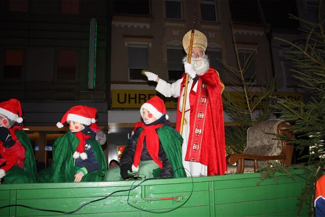 Der Nikolaus steht auf einen Wagen, Kinder sitzen ebenfalls dort.