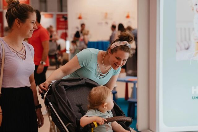 Eine Frau guckt in einen Kinderwagen