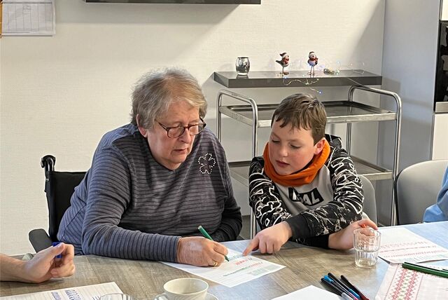 Simon hilft Giesela Barß bei den Schreibübungen im Kalligrafie-Workshop im Wohn- und Pflegezentrum Auguste Victoria.