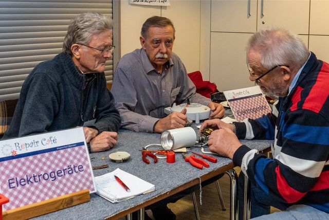 Hans Reuter, Günther Petrat und Norbert Becker reparieren eine elektrische Kaffeemühle.