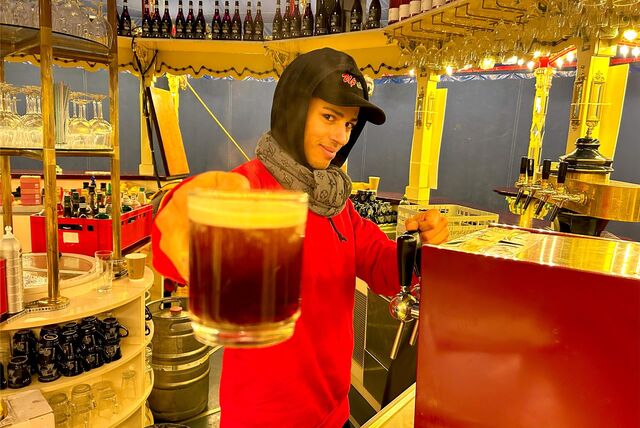 Ein Verkäufer hält in der Nostalgiebar in Recklinghausen einen Glühwein in die Kamera.