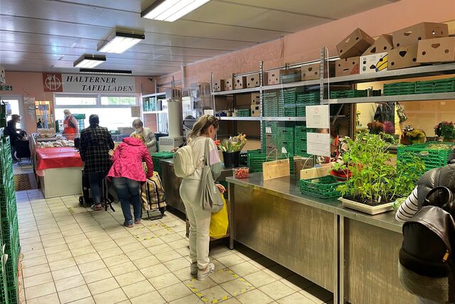 Mehrere Personen stehen im Tafelladen vor einer Theke, um Lebensmittel zu erhalten.