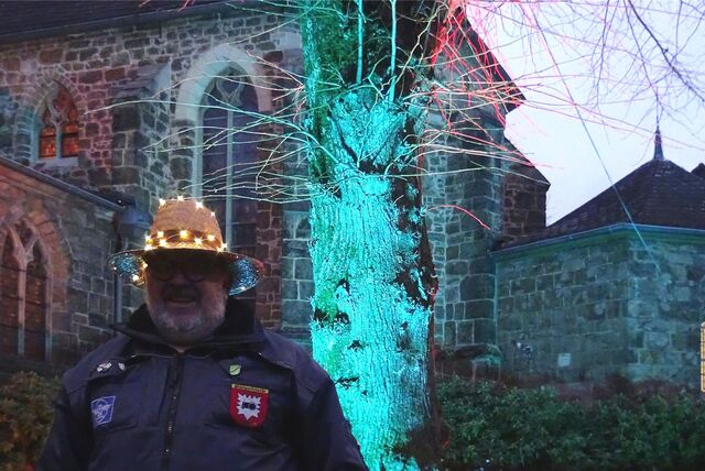 Mann mit Hut und Lampen vor beleuchteter Kirche