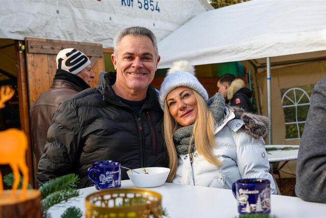 Ein mit Winterjacken bekleidetes Paar steht auf dem Speckhorner Weihnachtsmarkt in Recklinghausen an einem Bistrotisch und lächelt in die Kamera.