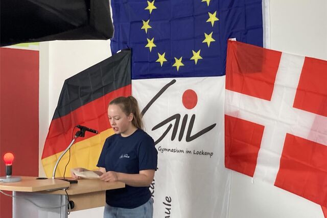 Vor dem Hintergrund mit deutscher, dänischer und Europaflagge stellt Inka Stockhorst ihre Frage an den dänischen Astronauten Andreas Morgensen.