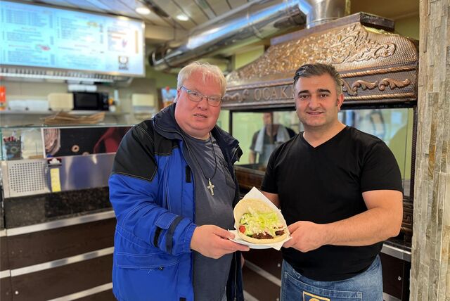 Thomas Frauendienst und Selam Tasdemir vom Topkapi Grill Ocakbasi posieren vor dem Grill zusammen für ein Foto. In der Hand halten sie gemeinsam einen Dönerteller.