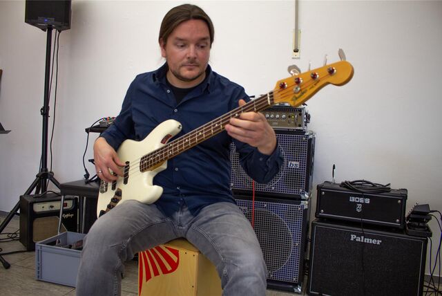 Musikschullehrer Jan Wolf spielt auf einem weißen E-Bass.