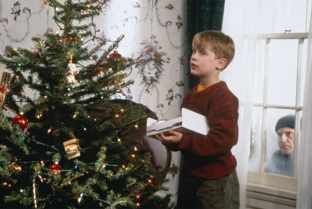 Eine Szene aus „Kevin – Allein zu Haus“: Kevin McCallister schmückt im Haus der Familie in Chicago den Weihnachtsbaum, während Harry, einer der „feuchten Banditen“, durchs Fenster ins Haus schaut.