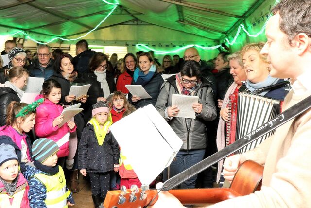 Zwei Musiker begleiten junge und alte Menschen beim Singen.