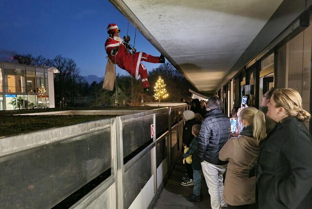 Ein Höhenretter der Feuerwehr seilt sich als Nikolaus verkleidet an der Dattelner Kinderklink ab. Auf dem Balkon stehen Menschen und schauen zu.