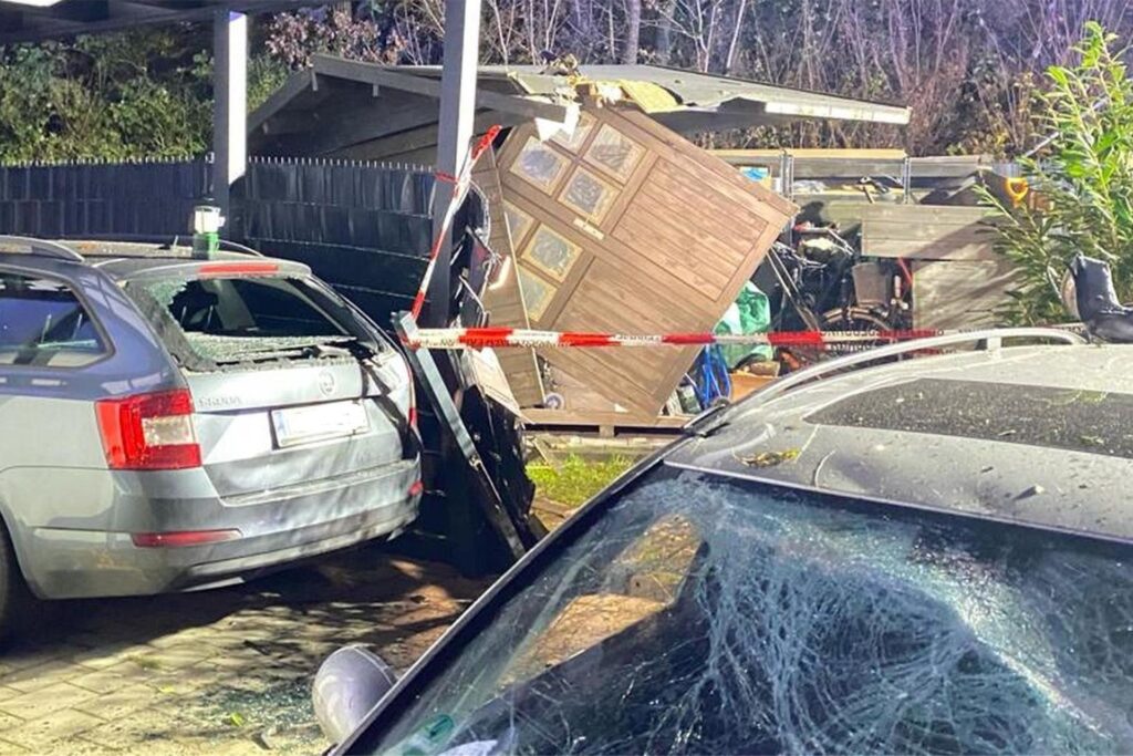 Eine zerstörte Gartenhütte, im Vordergrund zwei beschädigte Autos. Eine zerstörte Gartenhütte, im Vordergrund zwei beschädigte Autos.