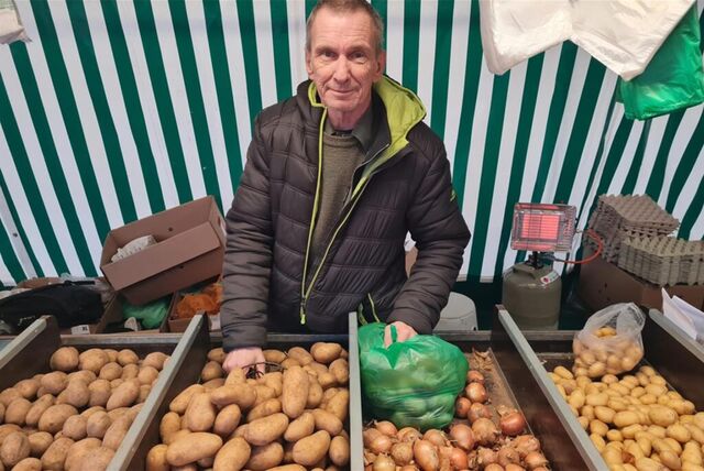 Mann steht vor Kisten mit Kartoffeln.