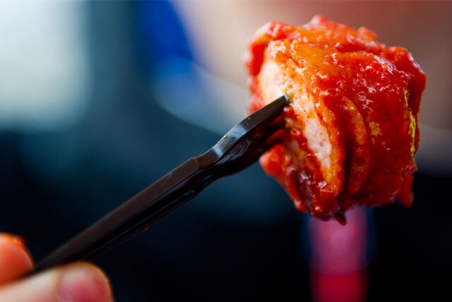 Eine Plastikgabel spießt ein Stück Wurst auf.