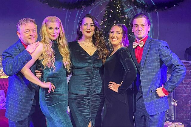 Zwei Männer und drei Frauen stehen nebeneinander auf einer Theaterbühne.