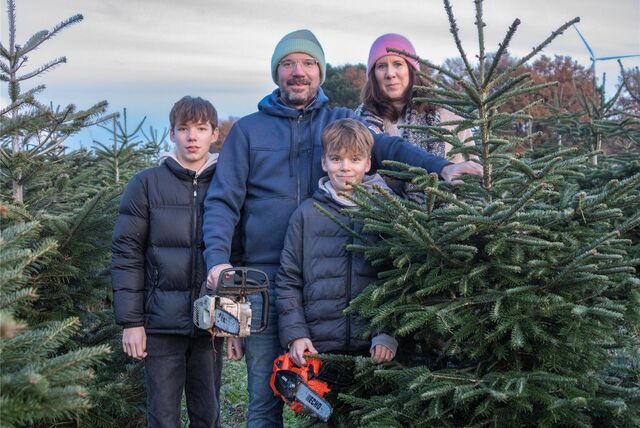 Zwei Kinder stehen mit ihren Eltern inmitten von Weihnachtsbäumen. (Archiv)