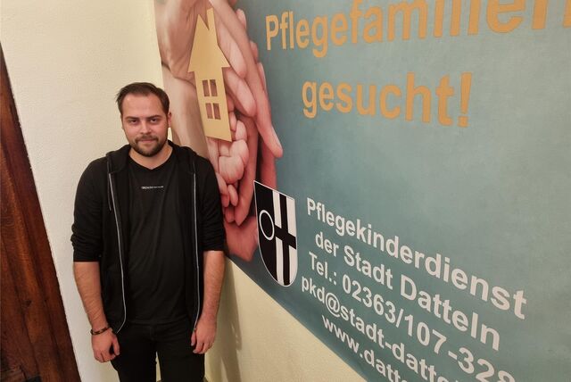 Ein Mann steht vor einem Plakat
