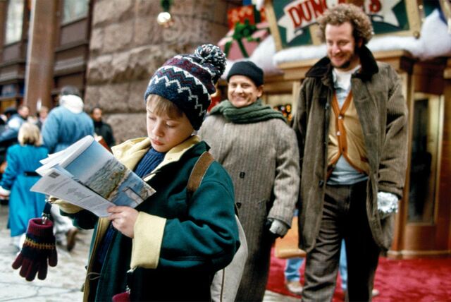 Eine Szene aus „Kevin allein in New York“: Kevin McCallister steht mit einem Stadtplan vor dem Spielwarengeschäft „Duncan’s Toys“, hinter ihm stehen die „feuchten Banditen“ Harry und Marv.