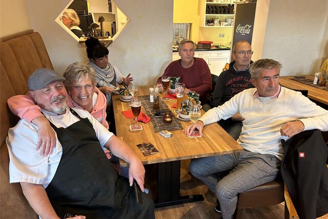 Menschen sitzen mit Getränken an einem Tisch.