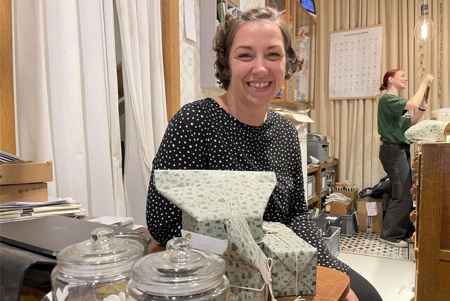 Mary Sander sitzt an einem Tisch mit verpackten Weihnachtsgeschenken im Format Warenwunderland in Recklinghausen