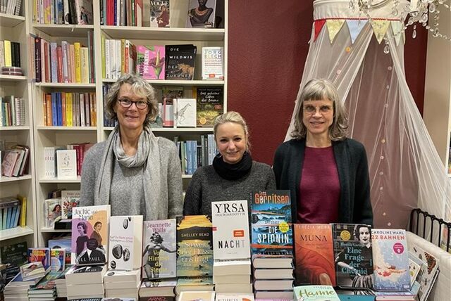 Drei Mitarbeiterinnen der Buchhandlung Leselust stehen vor einem Stapel Bücher.