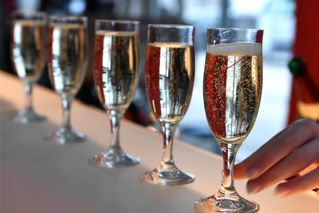 Fünf Sektgläser stehen gefüllt mit Sekt in einer Reihe. Fünf Sektgläser stehen gefüllt mit Sekt in einer Reihe.