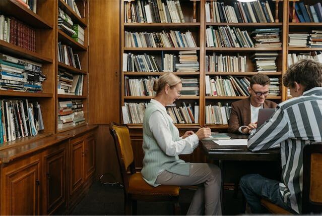 menschen sitzen in einer bibliothek und arbeiten