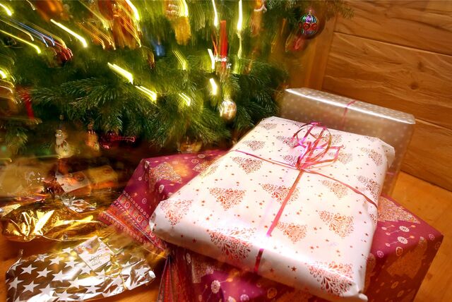 Geschenke liegen unter einem beleuchteten Weihnachtsbaum.