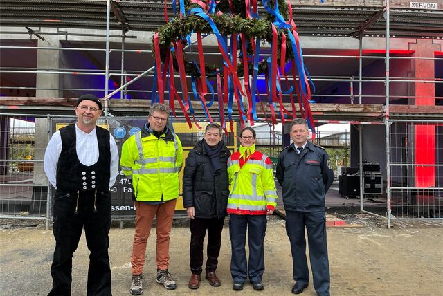 Der Richtkranz hängt vom Dach der neuen Rettungshalle: Das Richtfest feierten (v. l.) Polier Jürgen Janssen, Oberbauleiter Jörg Herrmann, Bürgermeister Werner Arndt, Katrin Wüller (ständige Vertreterin der Rettungsdienst-Leitung) und Feuerwehrchef Rainald Pöter mit gut 100 Gästen.