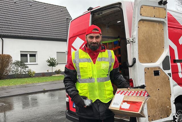 Wissam Ramadan mit Paket in der Hand vor seinem Transporter.