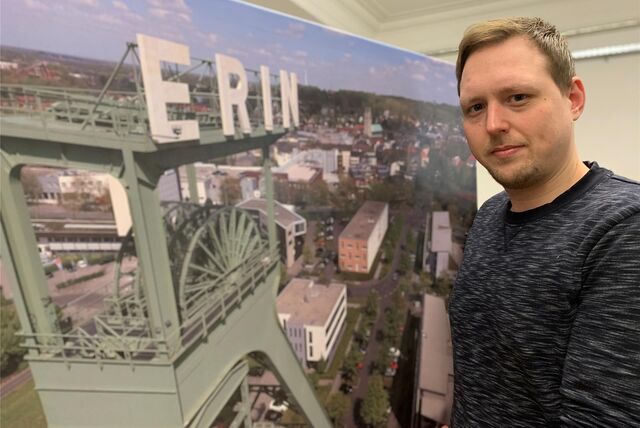 Redaktionsleiter Fabian Hollenhorst steht vor einem großformatigen Foto, das die Zeche Erin zeigt.