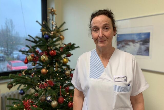 Krankenpflegerin Barbara Krüper steht vor einem weihnachtlich geschmückten Baum, der auf ihrer Station im EvK steht.