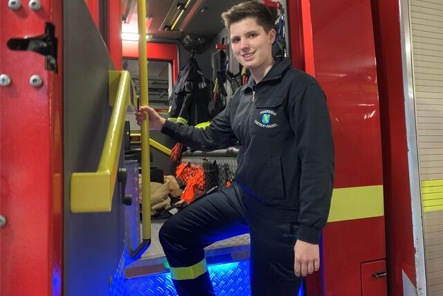 Mia Baum steht am Einstieg eines Feuerwehrwagens, in dem sich Ausrüstung befindet.