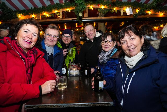 Eine Gruppe von Frauen und Männern steht an einem Glühweinstand auf dem Weihnachtsmarkt Recklinghausen.