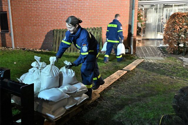 THW-Helferin trägt Sandsäcke.