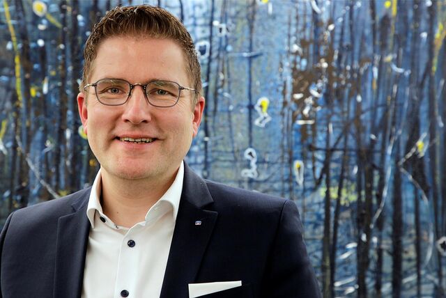 Volksbank-Vorstand Henning Henke steht vor einem Kunstwerk.