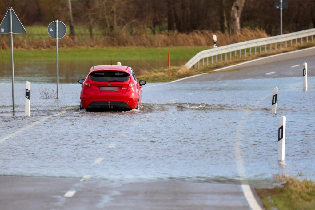 Auto fährt durch überflutete Straße