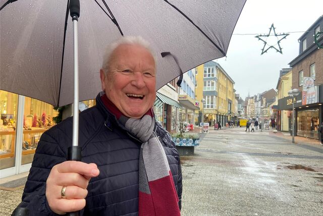 Ein älterer Mann mit Regenschirm steht in der Dattelner Fußgängerzone.