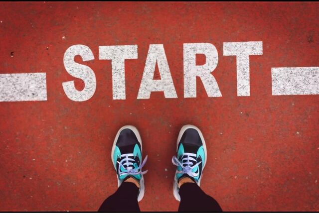 Eine Frau in Laufschuhen steht auf eine Laufbahn mit dem Text „Start“. Symbolbild, das Neujahrsvorsätze darstellen soll.