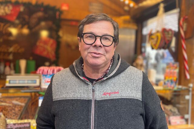 Patrick Arens steht vor einem Stand des Dortmunder Weihnachtsmarktes.