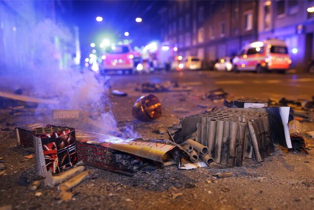 Abgebrannte Böller liegen auf der Straße. Im Hintergrund sieht man Blaulicht.