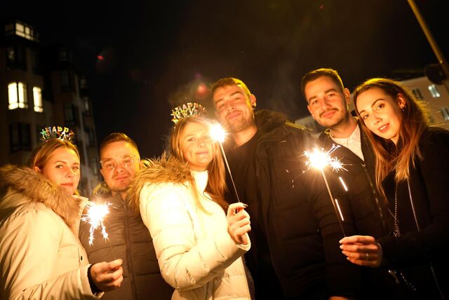 Man sieht eine Gruppe von sechs Menschen, wahrscheinlich drei Pärchen. Drei von ihnen halten eine Wunderkerze in der Hand.