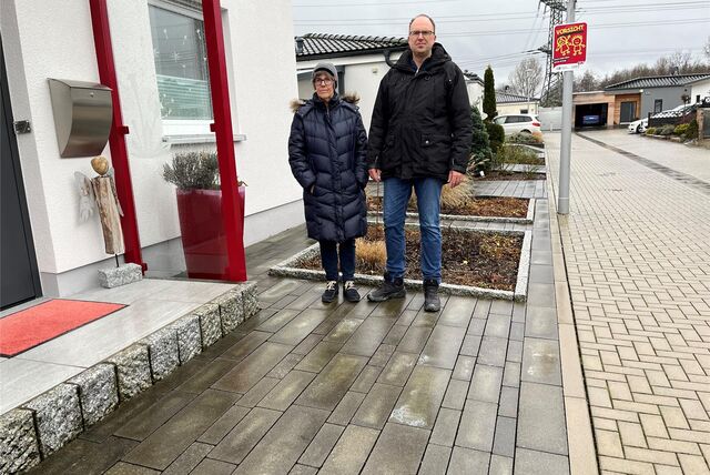 Marie Gerhardt und Dirk Gerhardt-Gräfe haben vor ihrem Haus statt eines Vorgartens einen Besucher-Stellplatz. Sie verweisen aber auf ein Beet (im Hintergrund), in dem die Pflanzen in wärmeren Jahreszeiten gedeihen
